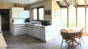 Una cocina con armarios blancos, un microondas y un comedor con mesa y sillas.