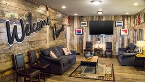 Un salon aux finitions en bois, agrémenté d’une pancarte « Bienvenue chez vous », de deux canapés, d’une table basse et d’un téléviseur à écran plat.