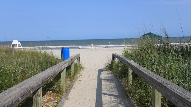 A sandy beach path leading to the ocean, with a lifeguard tower and a blue barrel visible. - Ocean View Studio + Mini Kitchen in Myrtle Beach (Myrtle Beach)