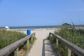A sandy beach path leading to the ocean, with a lifeguard tower and a blue barrel visible. - Ocean View Studio + Mini Kitchen in Myrtle Beach (Myrtle Beach)