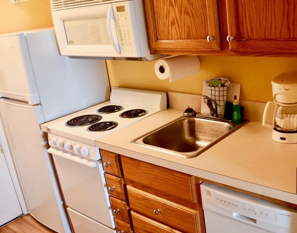 A compact kitchen with a stove, microwave, sink, and dishwasher. - Ocean View Studio + Mini Kitchen in Myrtle Beach (Myrtle Beach)