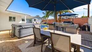 An outdoor patio area with a dining table, chairs, and a large umbrella. - Desert Oasis Retreat Pool Spa Gameroom (Scottsdale)