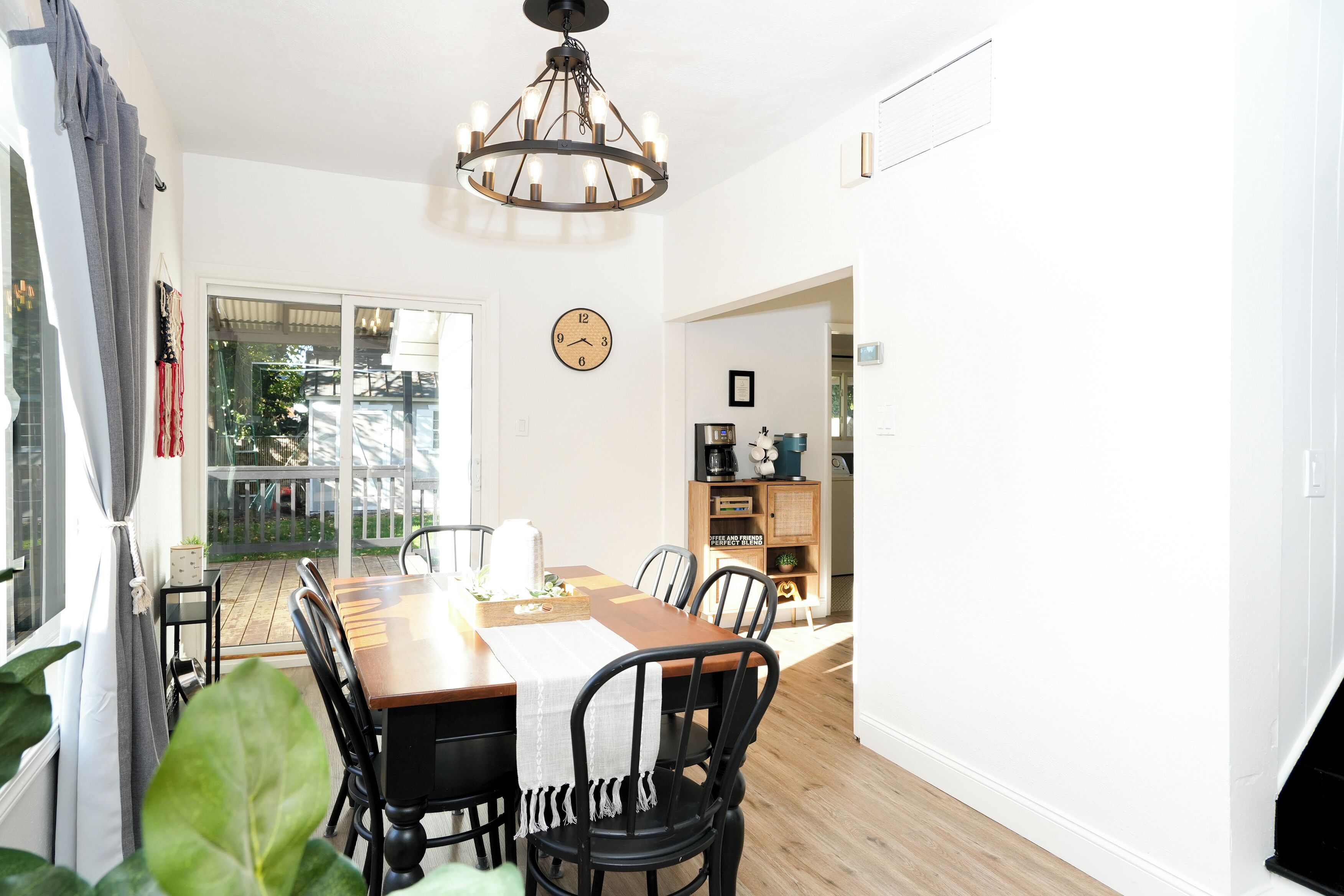 Un espace repas avec une table en bois, des chaises noires et un lustre.