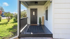 Un portico con una porta scura, un tappeto d'ingresso e una piccola pianta in vaso.