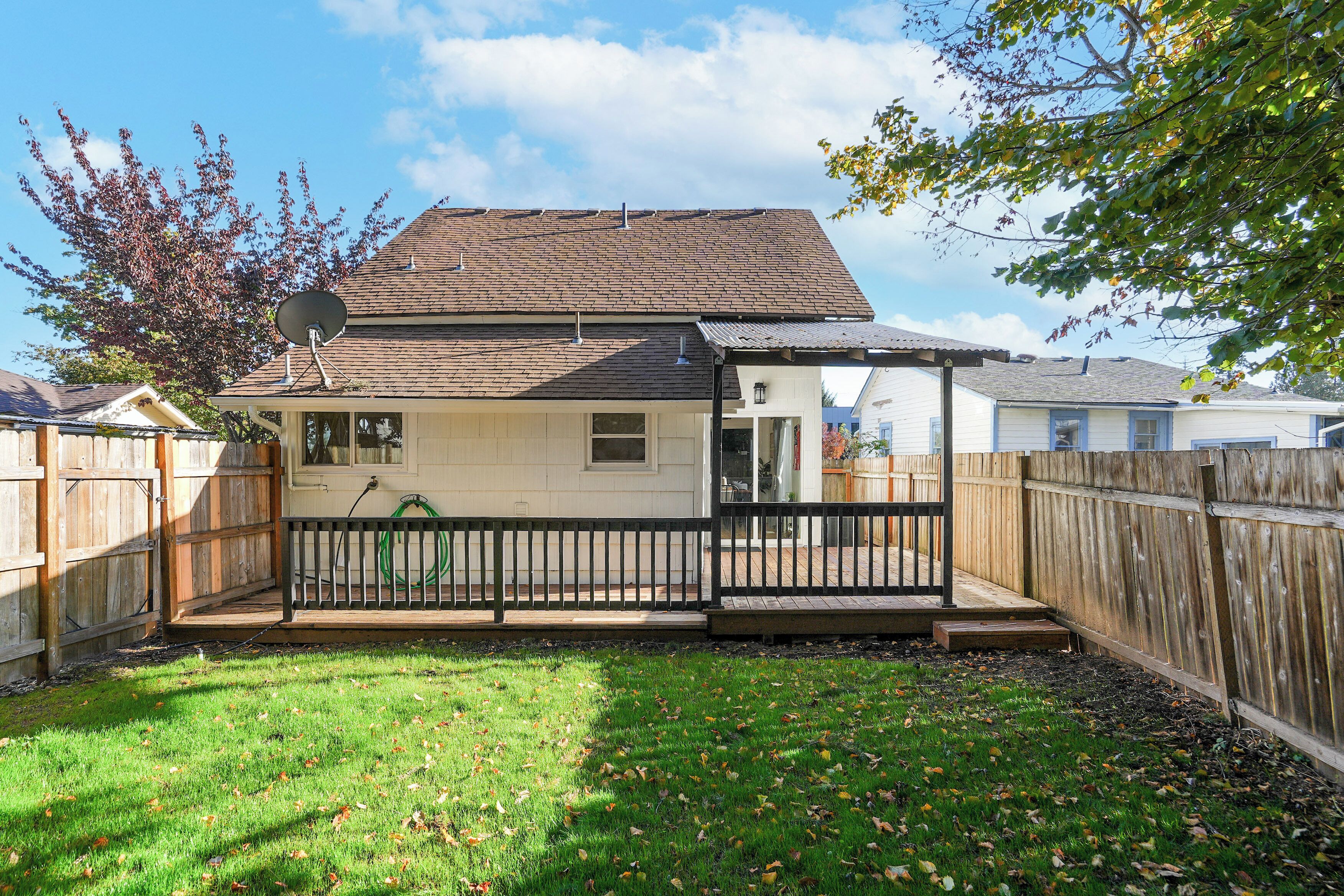A single-story house with a fenced backyard, a satellite dish, and a visible garage door.