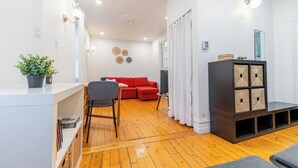 Un salon moderne avec un canapé rouge, un plancher en bois et un meuble de rangement intégré.