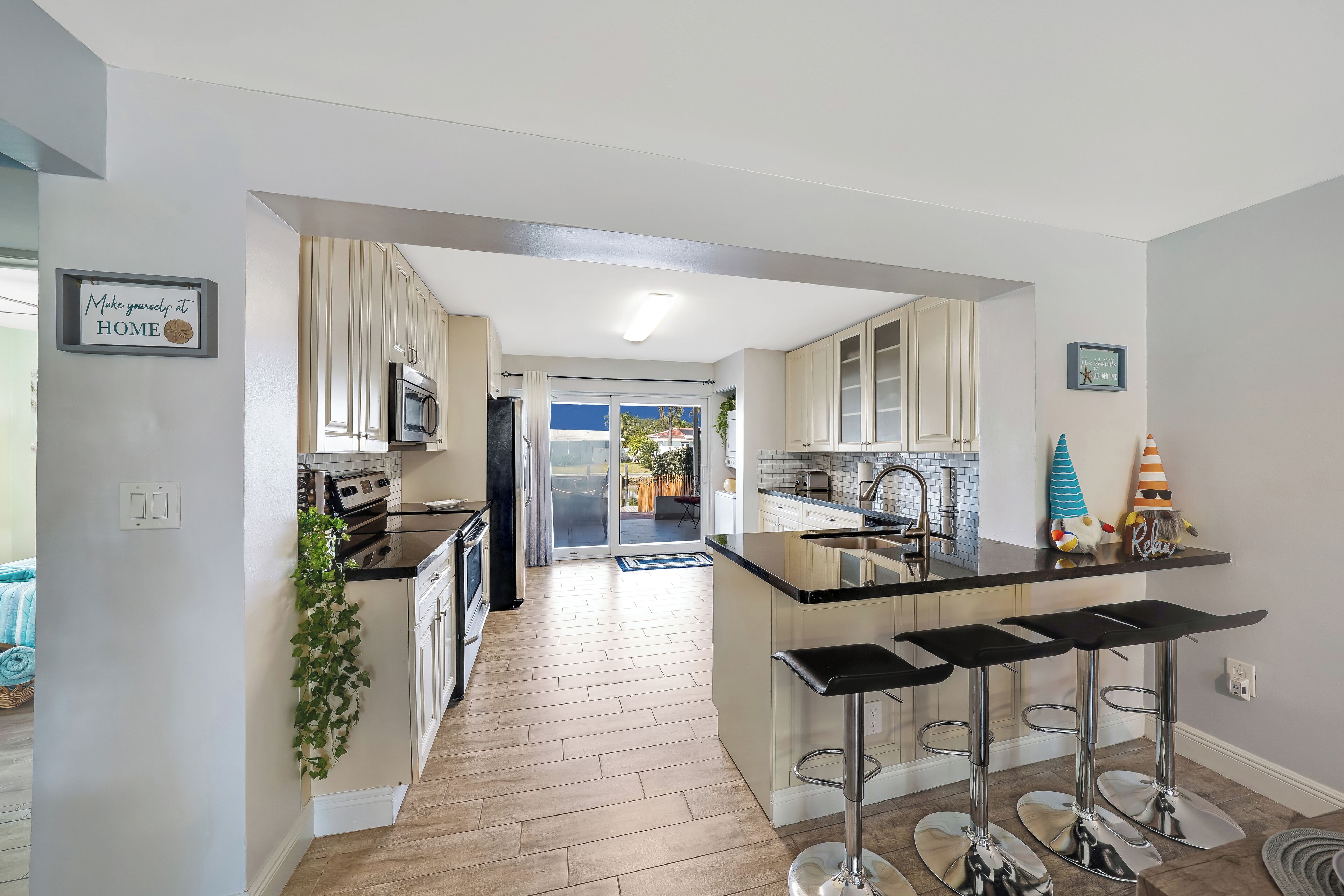 A modern kitchen with a central island, bar stools, and a view to the outside.
