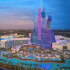 Un resort con un edificio con forma de guitarra, varias piscinas y una variedad de edificios del resort.