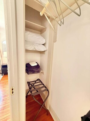 Ein Schrank mit Regalen zur Aufbewahrung, einer Kleiderstange und einem gefalteten Gegenstand auf der untersten Ablage.