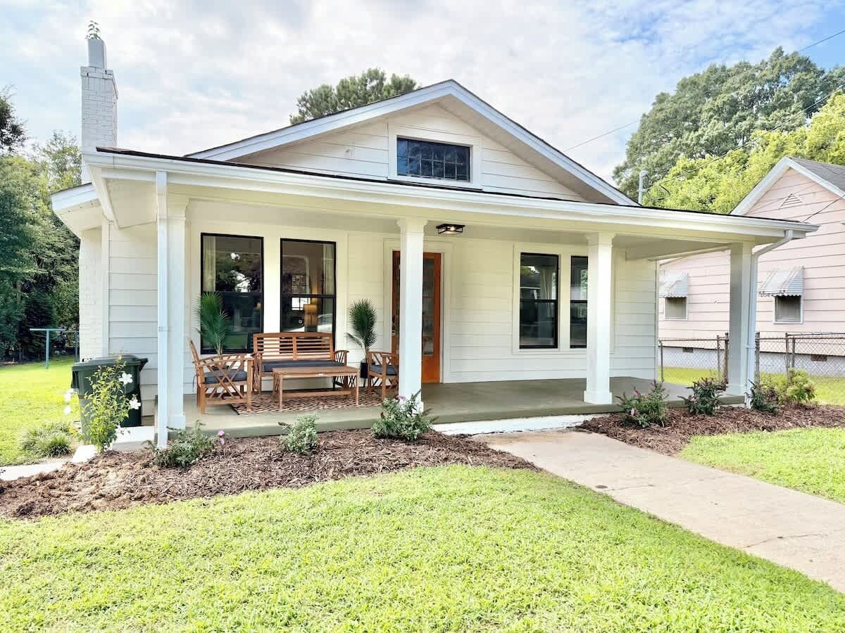 A single-story house with a covered porch, a chimney, and a well-maintained lawn.