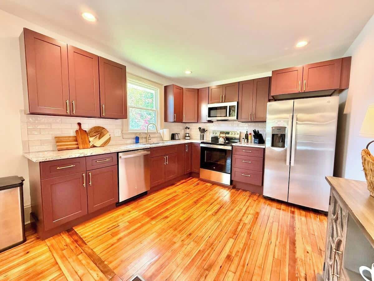A modern kitchen with wooden cabinets, a stainless steel refrigerator, and a microwave.