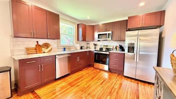A modern kitchen with wooden cabinets, a stainless steel refrigerator, and a microwave.