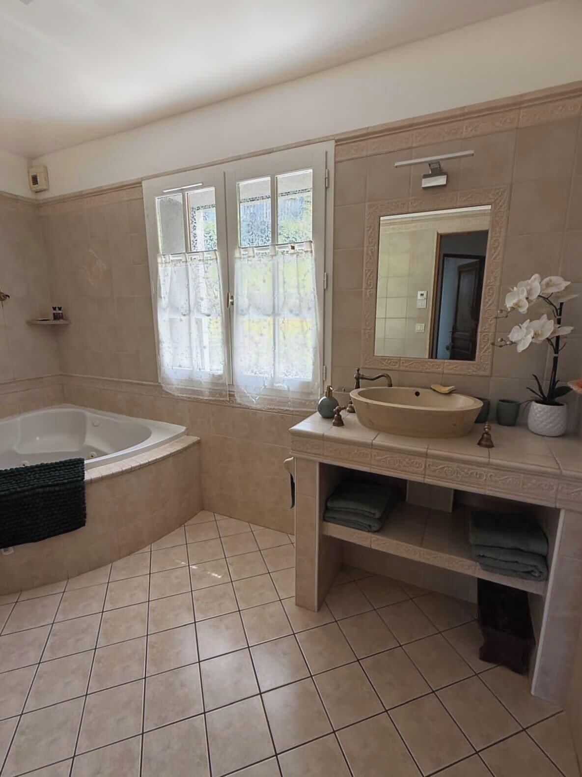 A bathroom with a bathtub, a sink, a mirror, and a window with curtains.