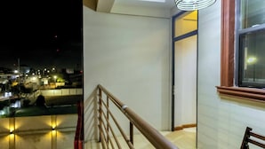 Une vue nocturne d’une ville, avec ses lampadaires et un immeuble doté d’un escalier et d’une fenêtre.