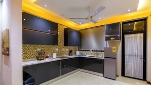 Une cuisine moderne avec des meubles de couleur sombre, un pare-feu en carrelage et un réfrigérateur en acier inoxydable.