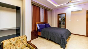 Une chambre à coucher comprenant un lit, une chaise, un ventilateur de plafond et un appareil de climatisation.