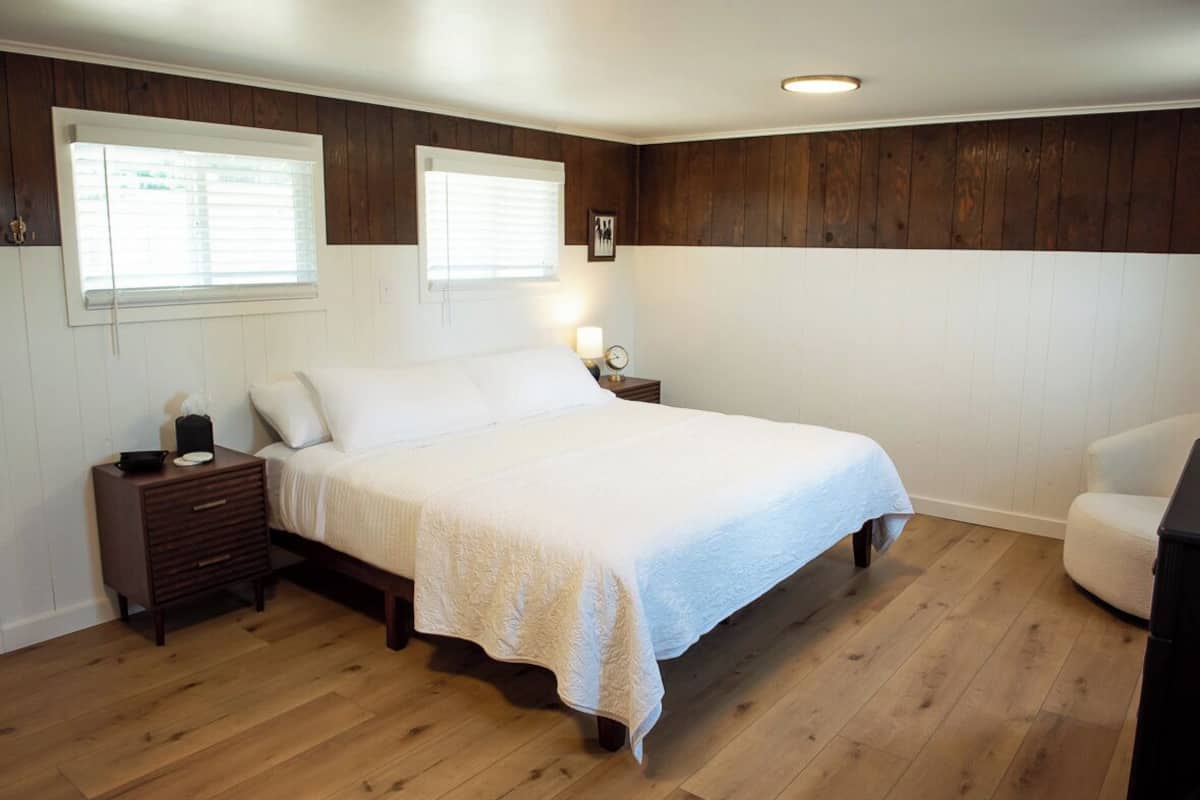 A bedroom with a large bed, two bedside tables, a nightstand, and a chair.