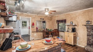 A kitchen with a wooden island, a brick fireplace, and a ceiling fan. - Cuddle Up In the Upper Canyon! (Ruidoso)