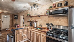 A kitchen with wooden cabinets, a stainless steel stove, and a microwave. - Cuddle Up In the Upper Canyon! (Ruidoso)