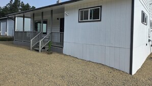 A single-story building with a covered porch and a small window. - Enjoyable 3-bedroom house with access to the beach (Long Beach)