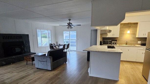 A modern kitchen with white cabinets, a central island, and a dining area with a sofa and chairs. - Enjoyable 3-bedroom house with access to the beach (Long Beach)