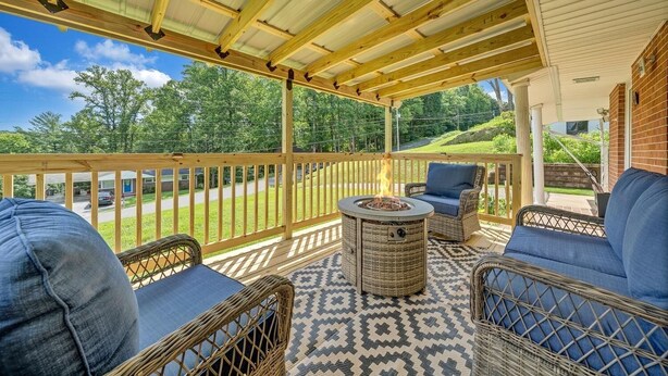 Un patio cubierto con mobiliario de mimbre, una chimenea y vistas a un paisaje verde.