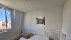 A bedroom with a bed, a radiator, a window, and a framed picture on the wall. - Studio Cozy Ivry near Paris (Ivry-sur-Seine)