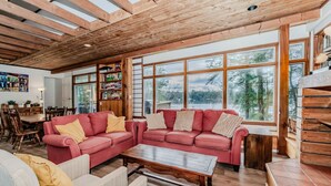 A cozy living room with a red sofa, a wooden coffee table, and a dining area with wooden chairs and a table.
