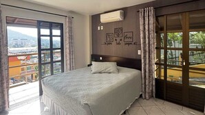 Un dormitorio con una cama grande, una puerta corrediza de vidrio a un balcón y un aire acondicionado instalado en la pared.