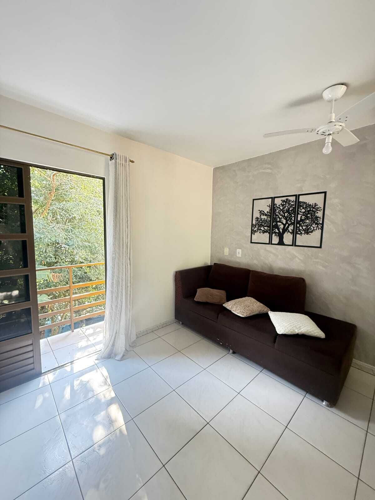A living room with a dark brown sofa, a ceiling fan, and a wall-mounted picture of three trees.