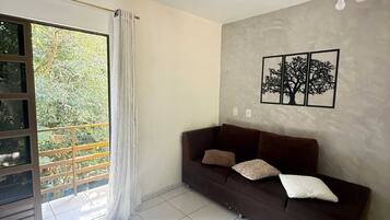 A living room with a dark brown sofa, a ceiling fan, and a wall-mounted picture of three trees.