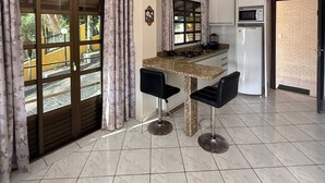Una cocina moderna con encimera de granito, dos taburetes de bar, un refrigerador y un microondas.