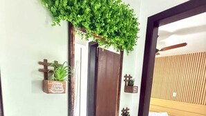 Un dormitorio con cama, mesita de noche y espejo en la pared con plantas.