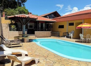 Propiedad residencial con piscina, patio de piedra y mobiliario exterior.