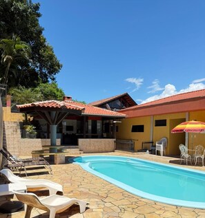 Ein Wohnhaus mit Swimmingpool, Liegestühlen und Gartenmöbeln.