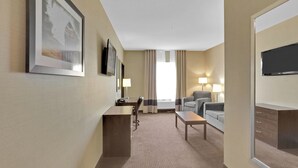 Ein Hotelzimmer mit Bett, Schreibtisch, Stuhl, Fernseher und einem Fenster mit Vorhängen.