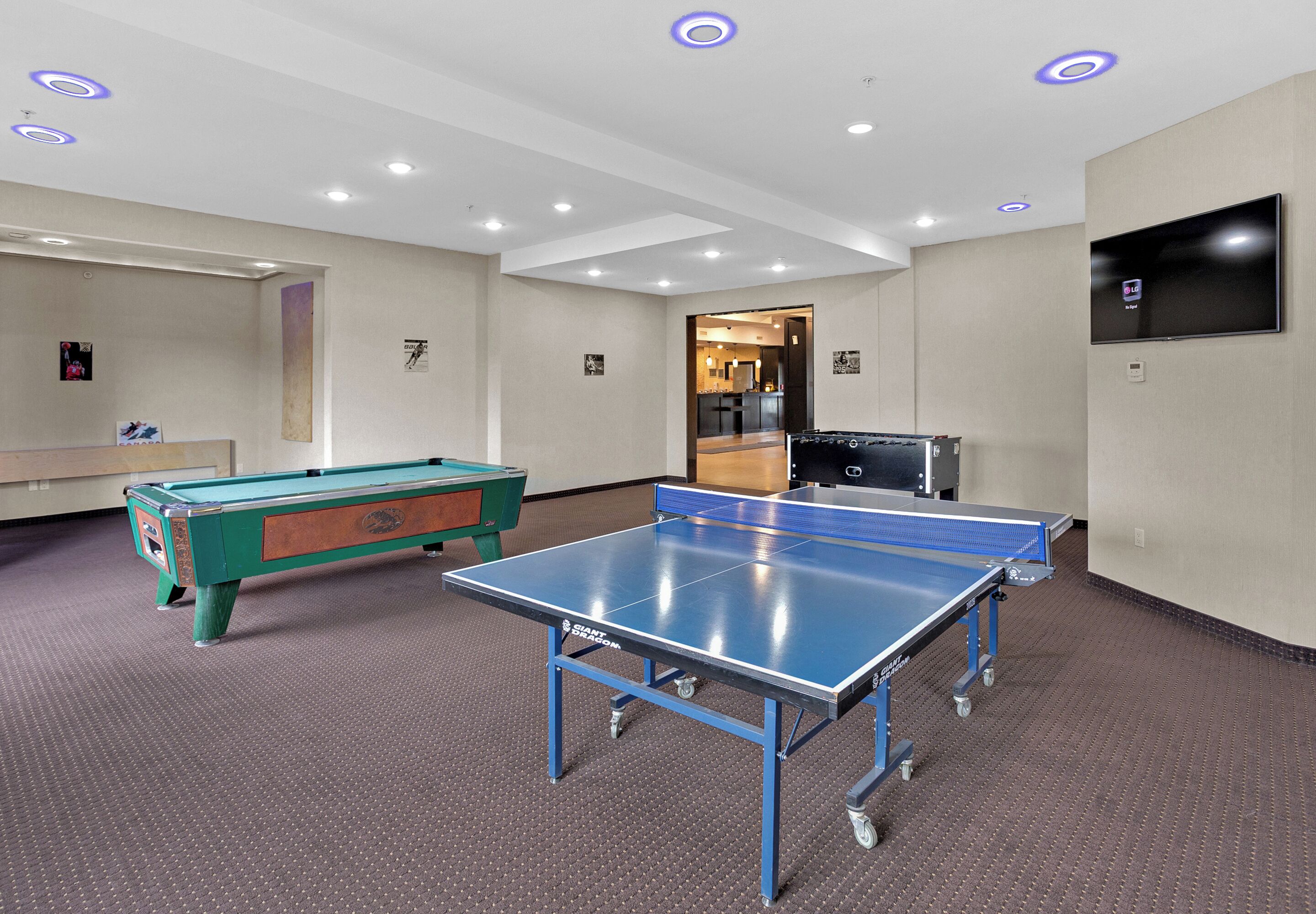 A room with a ping pong table, a pool table, and a billiards table.