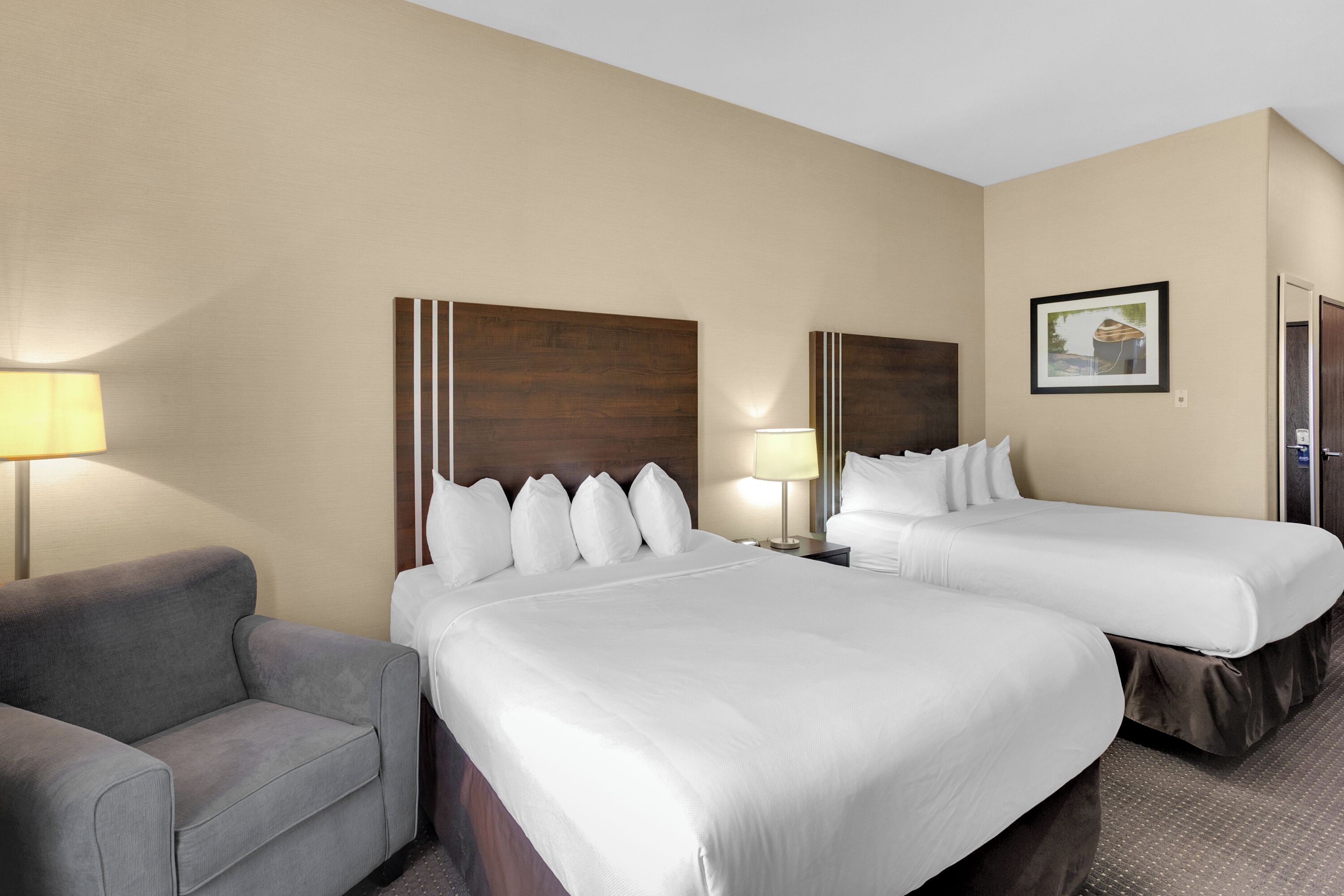 Una habitación de hotel con dos camas, un sofá y una lámpara.