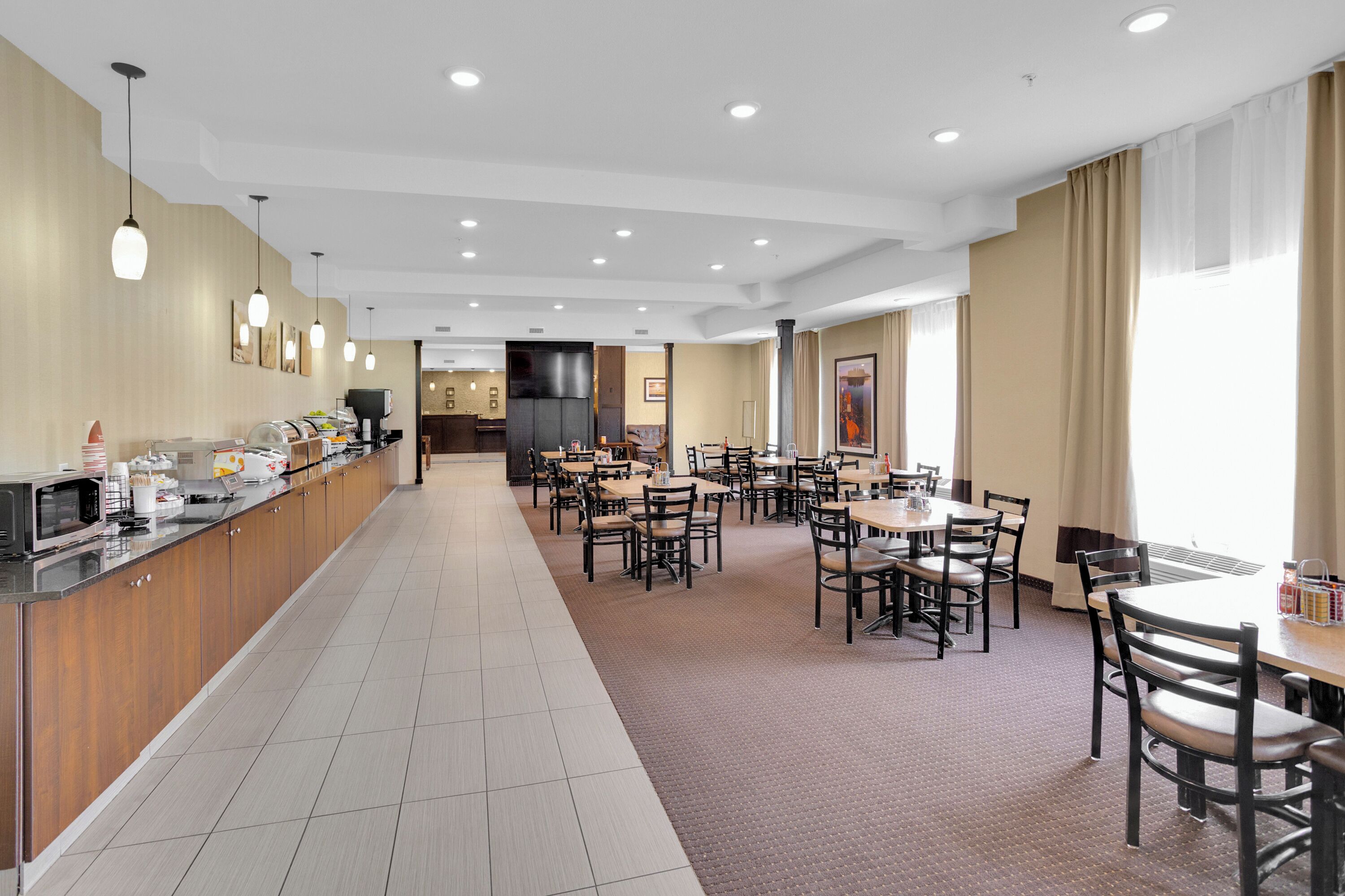 Un comedor de hotel moderno con una larga barra, varias mesas y sillas.
