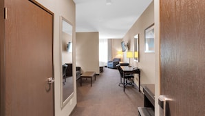 Ein Hotelgang mit Teppichboden, einem Schreibtisch, einem Stuhl, einem kleinen Tisch und einer Bank.