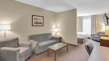 Ein Hotelzimmer mit grauem Sofa, einem Holztisch und einem Fernseher auf einem Schrank.