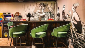 A bar area with green bar stools, arcade games, and a mural on the wall.