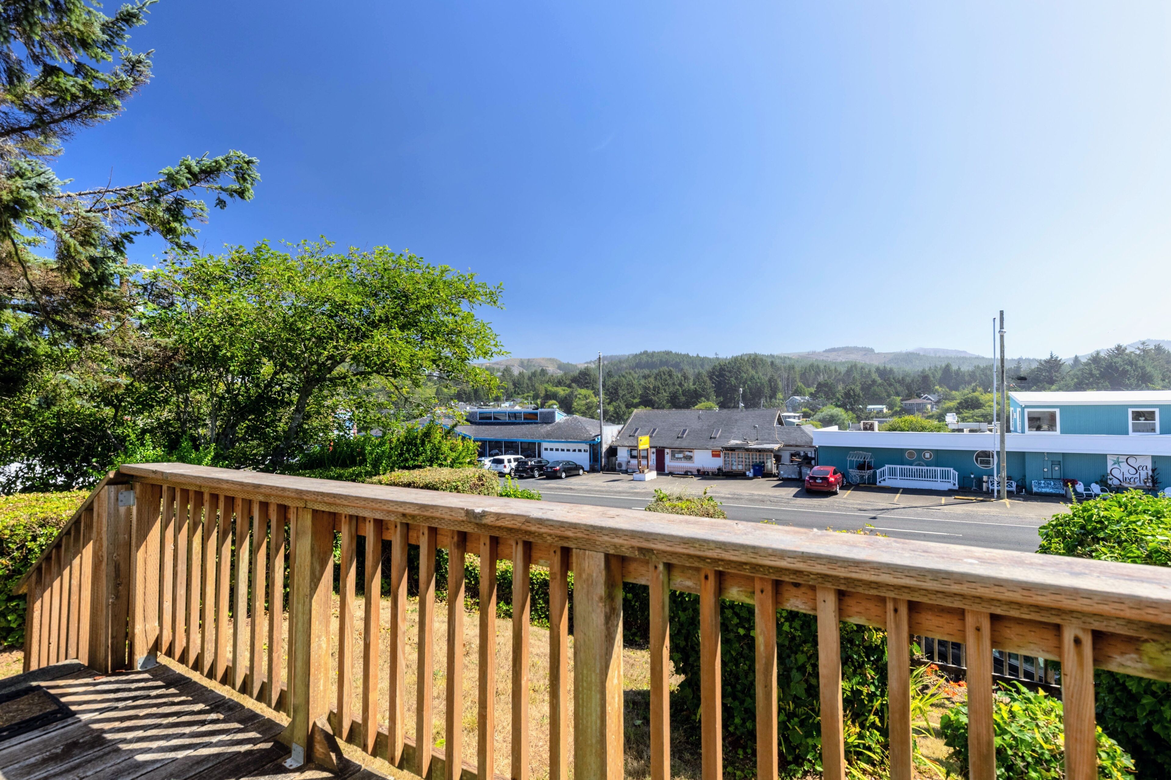 A wooden deck overlooking a parking area with a building in the background.