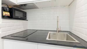 Een moderne keuken met een zwart aanrecht, een roestvrijstalen spoelbak en een magnetron.