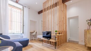 Een moderne woonkamer met een blauwe bank, een houten tv-meubel en een houten scheidingswand.