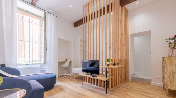 Un salon moderne avec un canapé bleu, un meuble TV en bois et une cloison en bois.