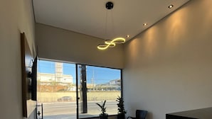 Un espace d’accueil moderne doté d’une grande fenêtre, d’un comptoir de réception et de deux plantes en pot.