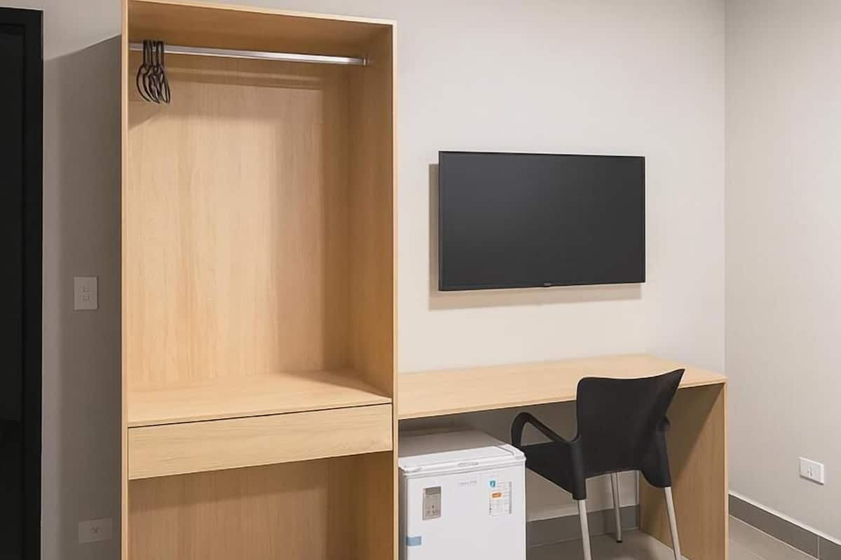 A bedroom with a bed, a desk, a chair, and a wardrobe.