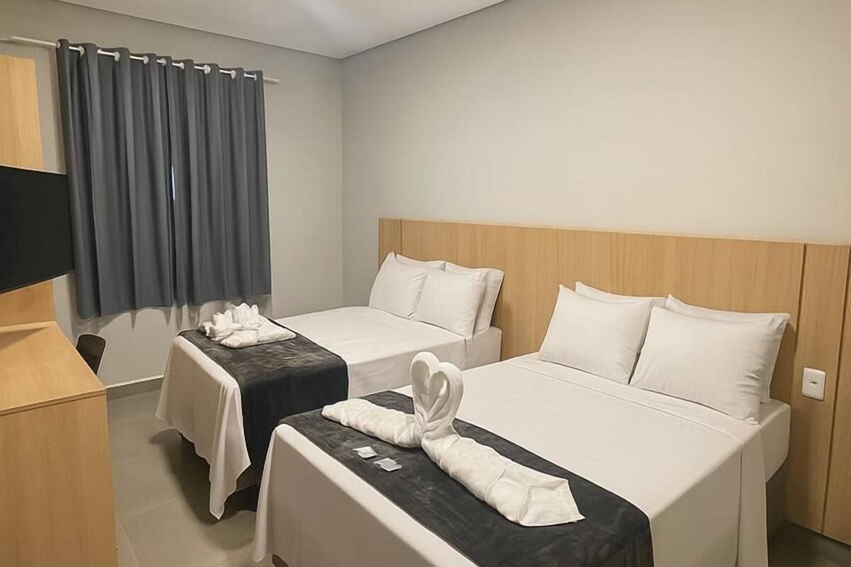 A hotel room with two beds, a TV, and a desk.