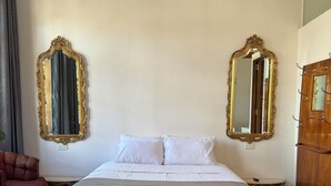 A bedroom with a large bed, two ornate mirrors, a wooden wardrobe, and a small table. - Fantastic Restored Patrimonial Suite (Cuenca)